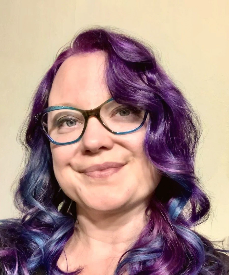 Jessica L Drake with purple hair and glasses.