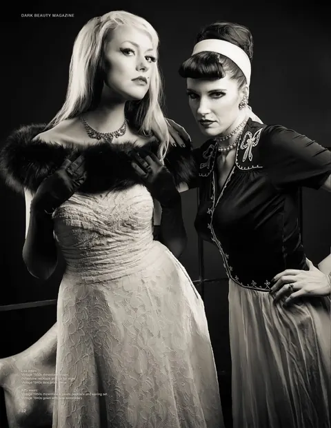 Black and white editorial portrait of two figures in formal styling.