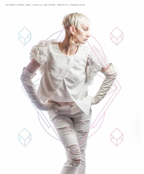 Katie Joy in a Finder's Keepers white textured top with ruffled organza shoulders, distressed white jeans, and long opera gloves, hexagonal cube graphics layered behind her.
