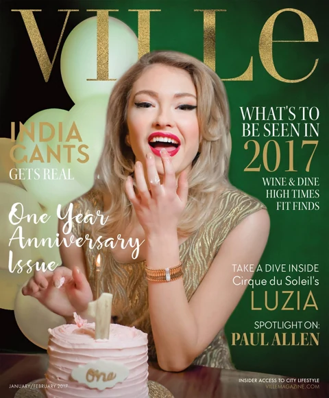 VILLE Magazine cover, One Year Anniversary Issue January/February 2017: India Gants in a gold zebra-print top, laughing as she blows out a "1" candle on a small pink anniversary cake, white balloons and emerald green backdrop behind her.