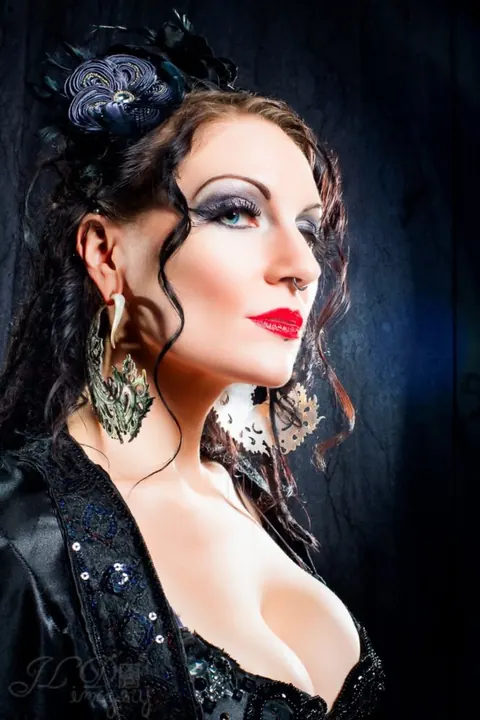 Beauty portrait with a blue floral fascinator, graphic eyeliner, and red lipstick.