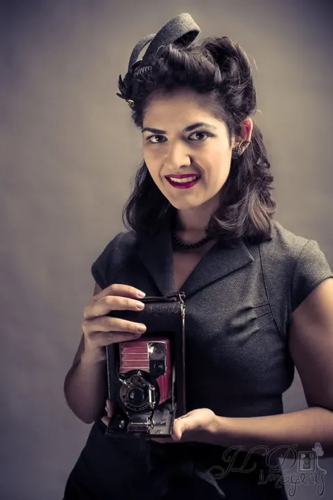 Vintage-styled beauty portrait holding a twin-lens camera.