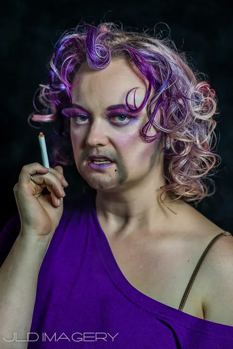 Expressive beauty portrait in violet light with drifting smoke.