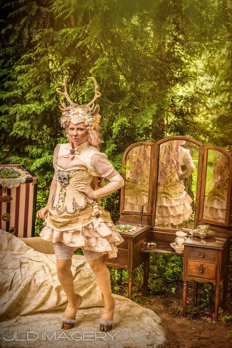 Antlered fantasy character standing beside a vintage vanity in the forest.