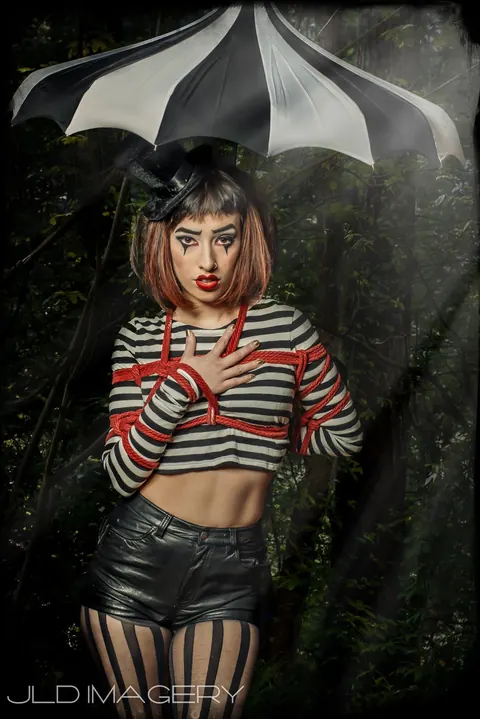 Theatrical woodland portrait beneath a black bat-wing umbrella.