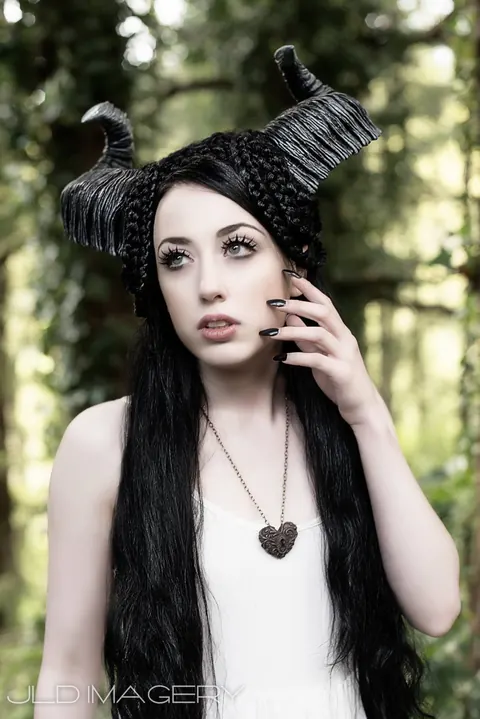 Woodland portrait with black sculpted horns and a pale dress.