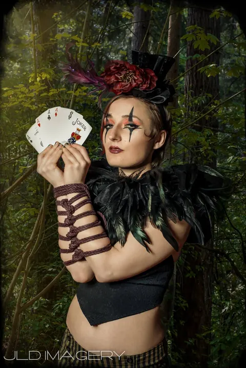 Close woodland fantasy portrait holding a fan of playing cards.