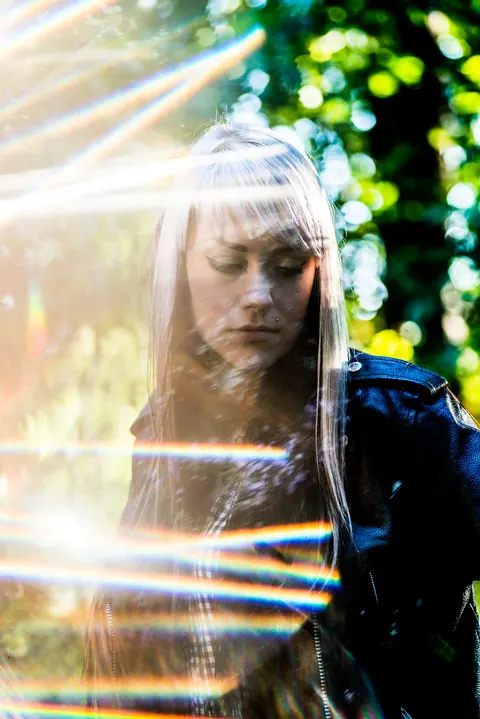 Portrait seen through layered rainbow prisms in a wooded setting.