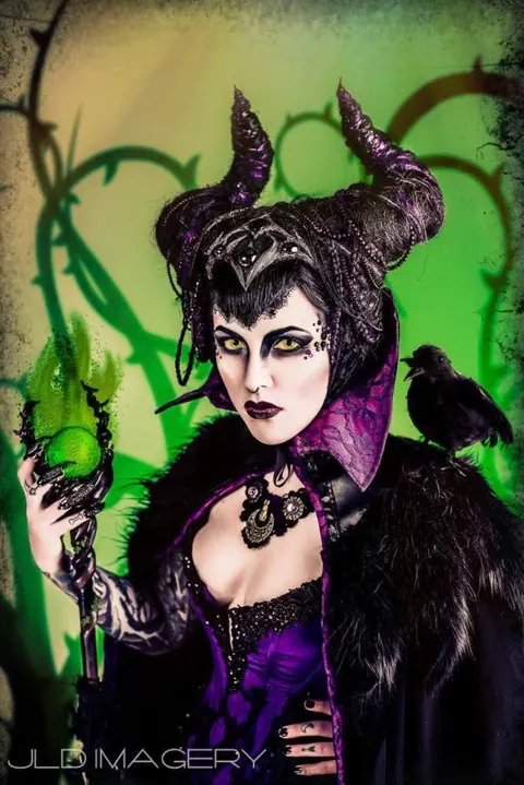 Dark fantasy portrait with a horned headdress, ravens, and green light.