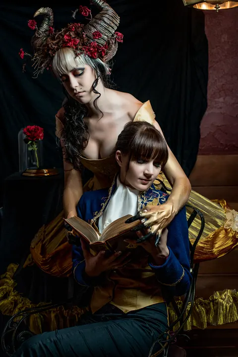 Elaborately costumed adult and child posed together in a storybook scene.