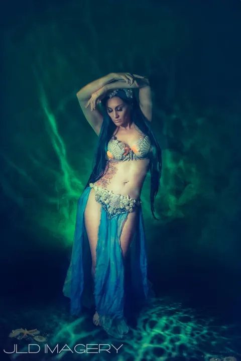 Full-length underwater fantasy portrait surrounded by teal light.