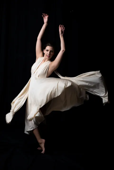 Dancer in a flowing white dress suspended against a black background.