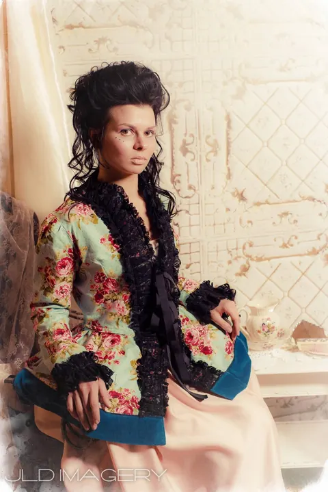 Period fashion portrait seated with a blue hand fan.