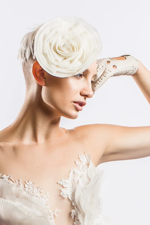 Portrait in a white floral headpiece, white glove, and white clothing against a white background.
