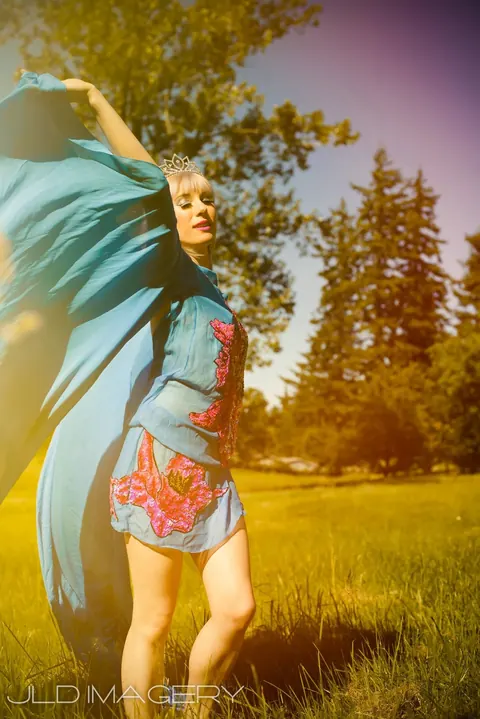 Fashion portrait in a teal and floral dress moving through a sunlit field.