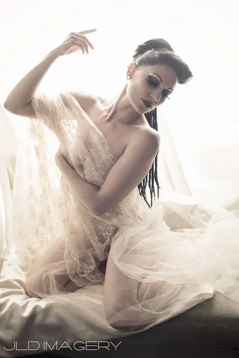 Bright fashion portrait in white lace with one arm raised.