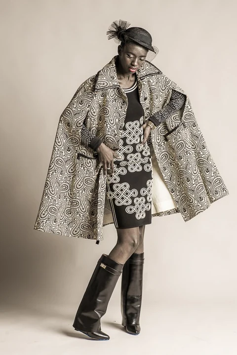 Full-length fashion portrait in a patterned cape and boots.