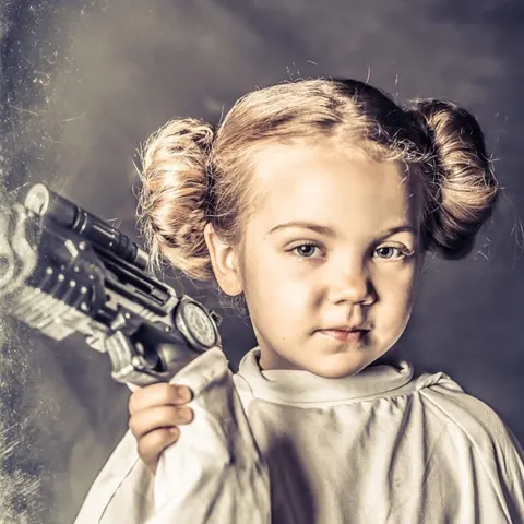 Young subject in a retro science fiction portrait holding a prop ray gun.