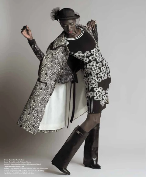 Binta Diba mid-stride in a Diane Von Furstenburg studded paisley jacket, knot-print dress, and Gidgette Bardot vintage cape, with knee-high Givenchy boots and a black veiled hat with bow.